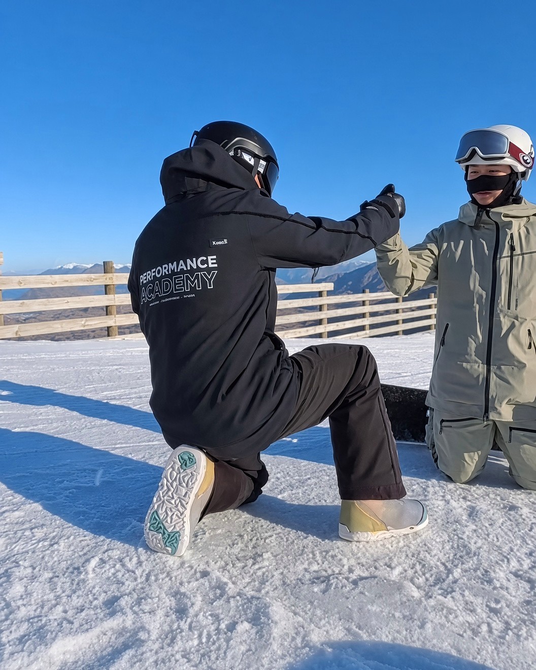 Instructor με μαύρο Performance Academy jacket κάνει fist bump σε μαθητή στο χιόνι