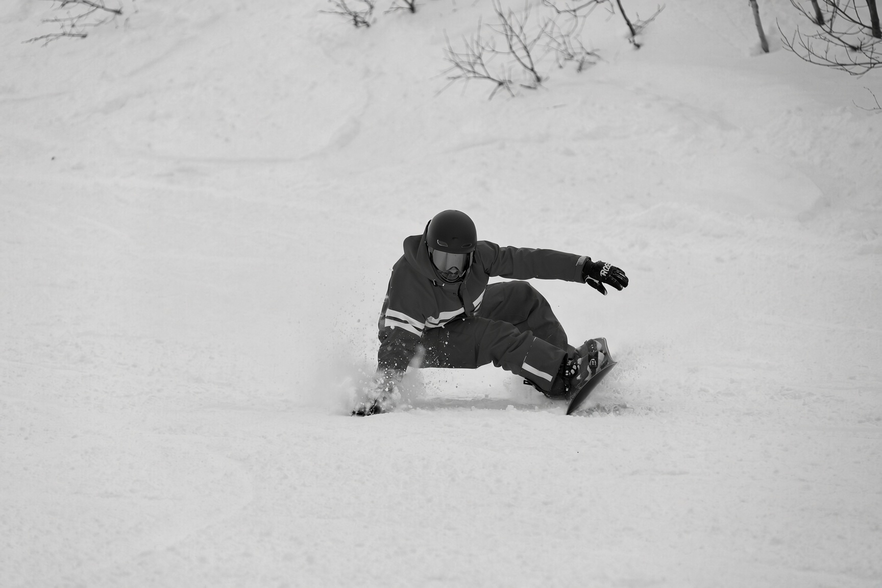 Snowboarder κάνει carve σε χιονισμένη πλαγιά σε ασπρόμαυρη φωτογραφία